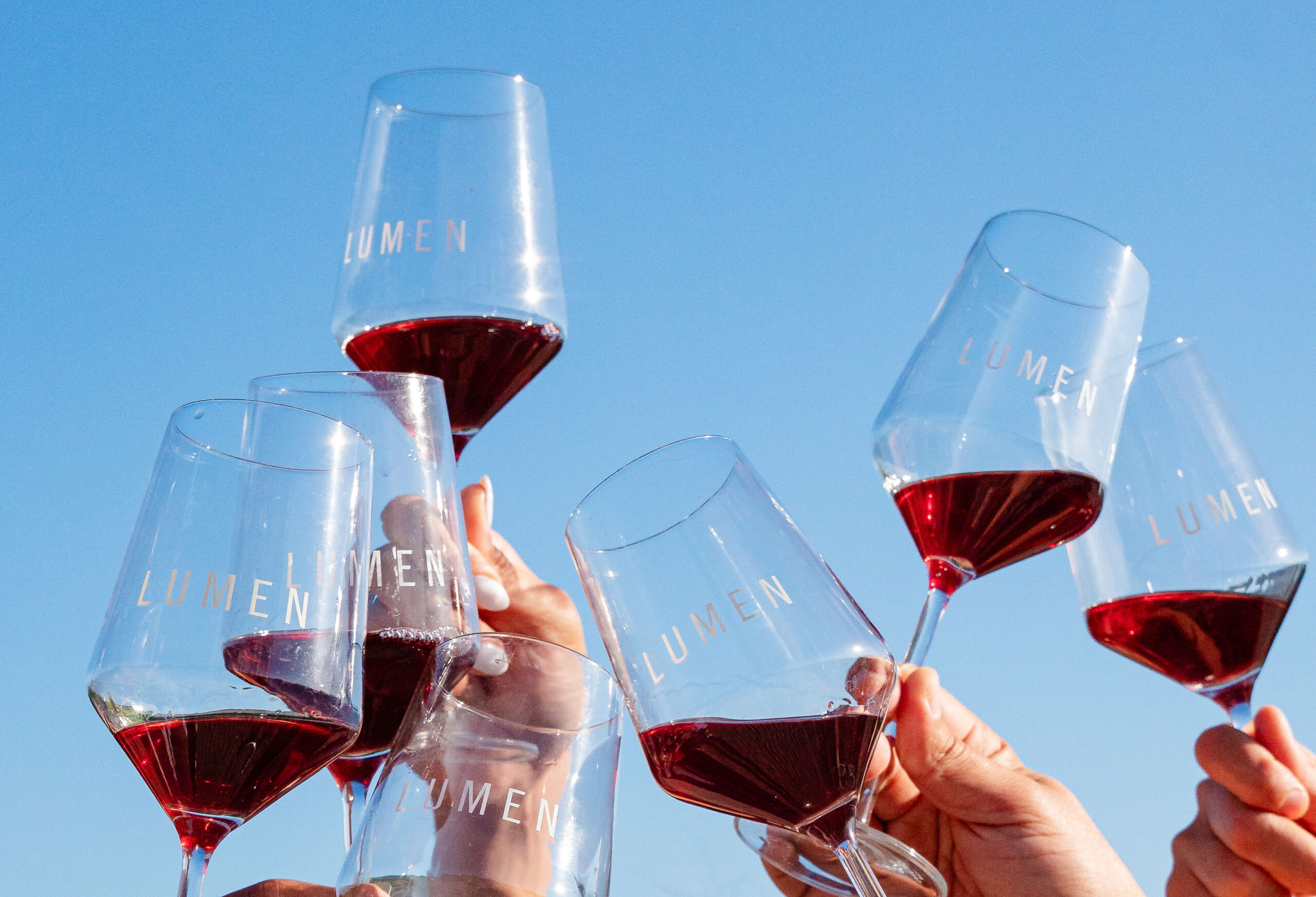 Wine glasses full of Pinot Noir cheering in front of a blue sky